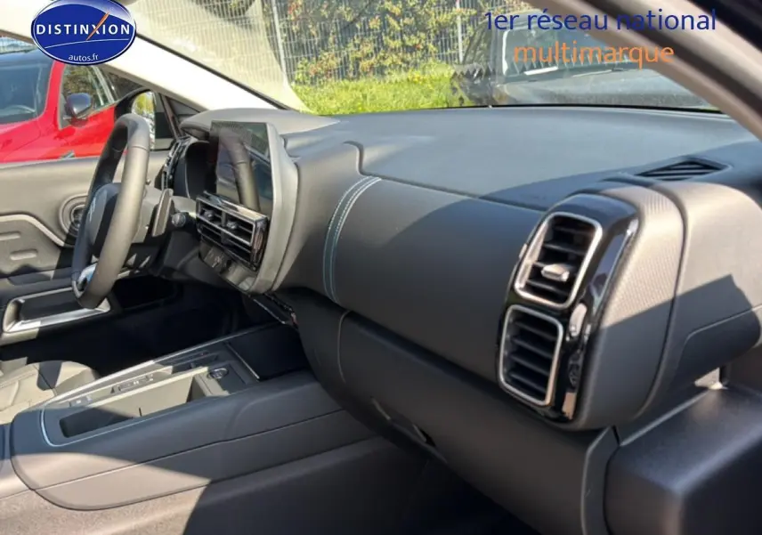 Intérieur du Citroën C5 Aircross 2025 vu côté passager, tableau de bord noir avec surpiqûres bleues et écran tactile central.