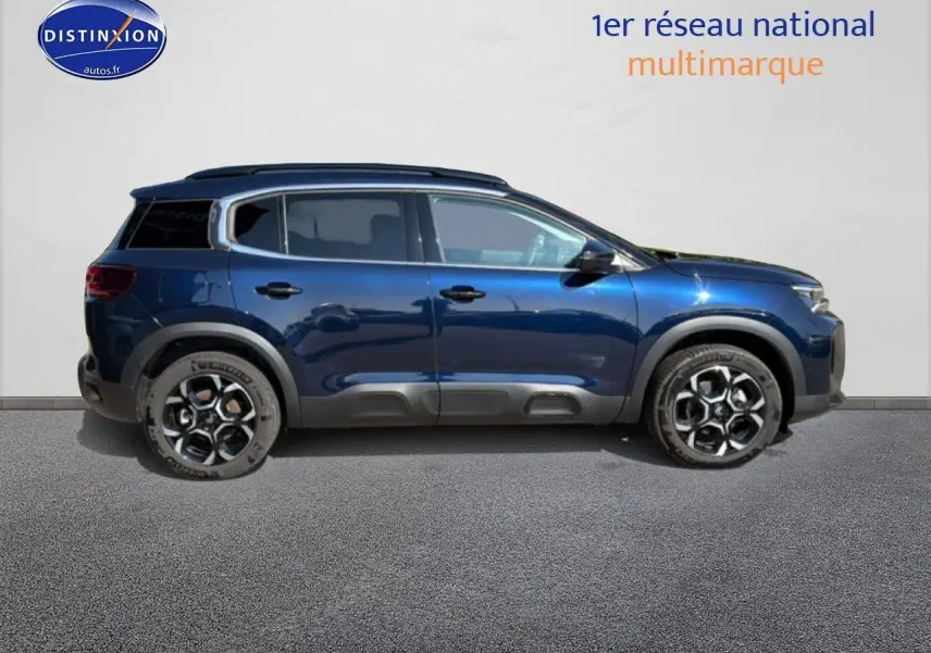 Profil droit d'un Citroën C5 Aircross bleu eclipse 2025 avec barres de toit et jantes alu distinctives.