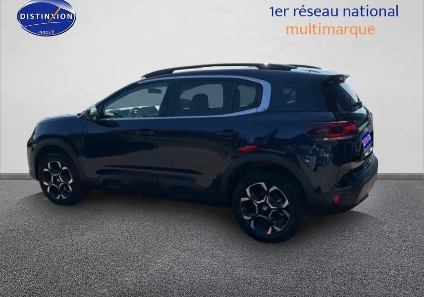 Vue latérale gauche d'un Citroën C5 Aircross bleu eclipse avec jantes alu et barres de toit noires.