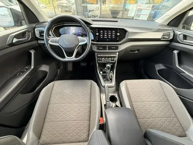 Vue intérieure frontale du tableau de bord et des sièges gris tissu du Volkswagen T-Cross 1.0 TSI R-Line Tech 2023.