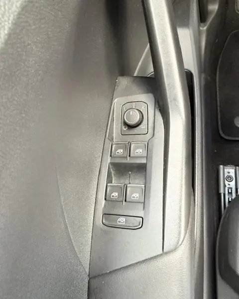 Détail des commandes de lève-vitres et réglage des rétroviseurs sur la porte côté gauche du Volkswagen T-Cross gris foncé.