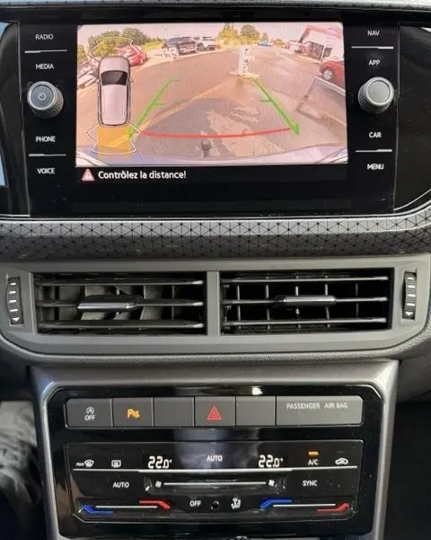 Affichage caméra de recul sur écran tactile du tableau de bord d’un Volkswagen T-Cross gris foncé, avec commandes climatisation et ventilation visibles.