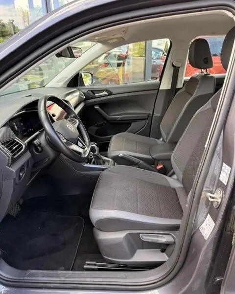 Vue intérieure côté conducteur du Volkswagen T-Cross gris foncé 2023, sièges tissu Hexalink et tableau de bord digital.