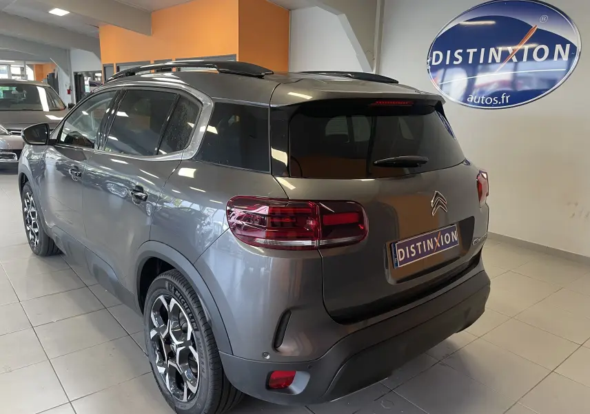 Vue rapprochée de l'écran tactile central noir brillant du tableau de bord du Citroën C5 Aircross gris platinium hybride 2025.