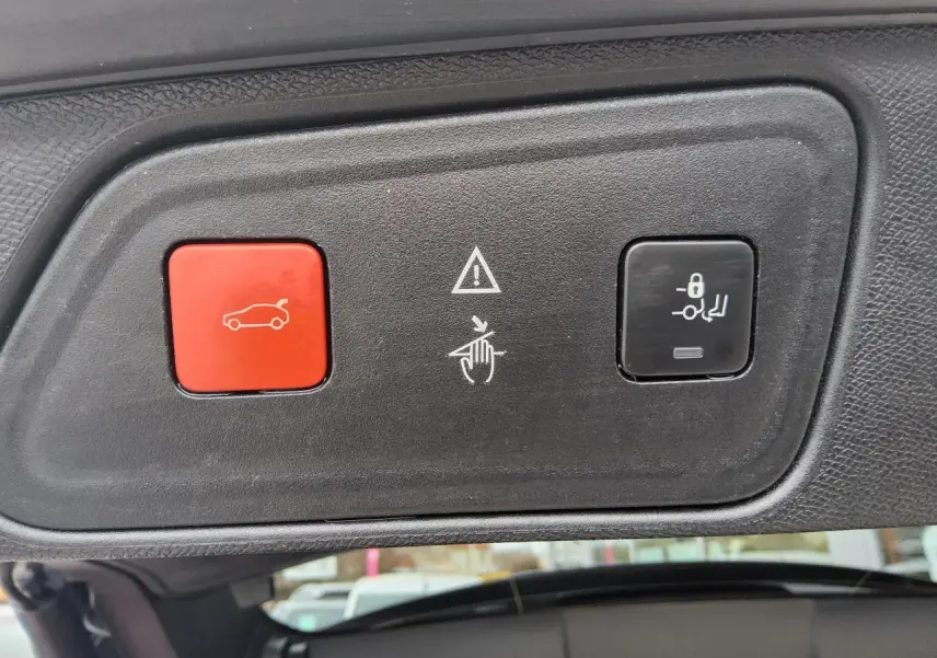 Gros plan sur les boutons de commande du hayon mains libres du Peugeot 3008 rouge foncé, intérieur du coffre visible.