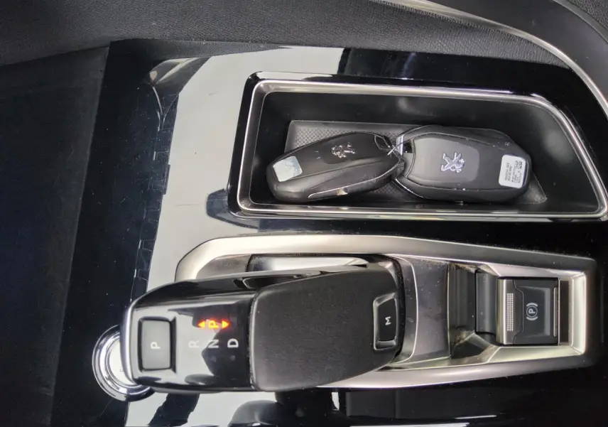 Gros plan sur la console centrale noire brillante du Peugeot 3008 2019 avec levier de boîte auto et clés.