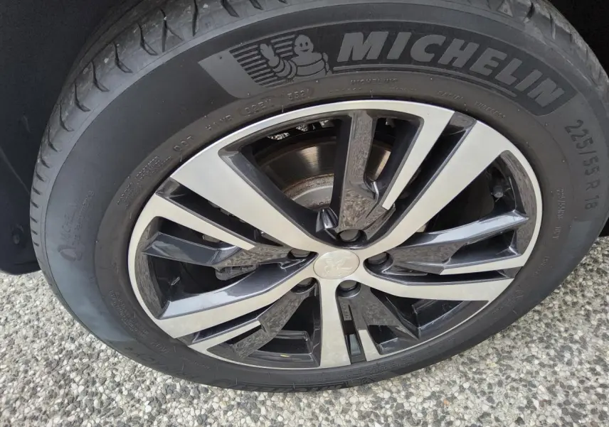 Gros plan sur la jante alliage 18 pouces bi-ton diamantée d’un Peugeot 3008 rouge foncé, pneu Michelin visible.