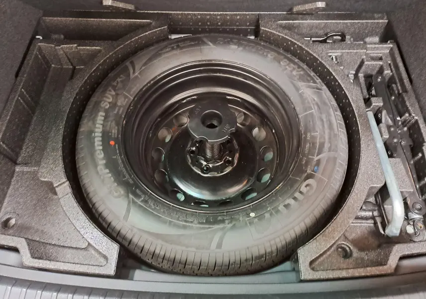 Gros plan sur la roue de secours galette dans le coffre du Skoda Karoq 2023, version Business gris perle.