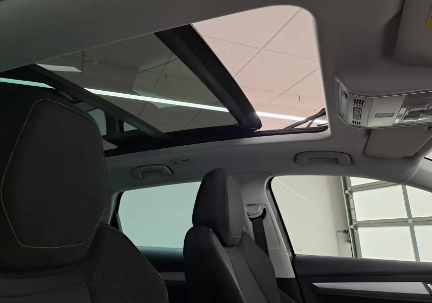 Vue intérieure du toit ouvrant panoramique du Skoda Karoq 2023, avec sièges avant en tissu noir et ciel de toit clair.