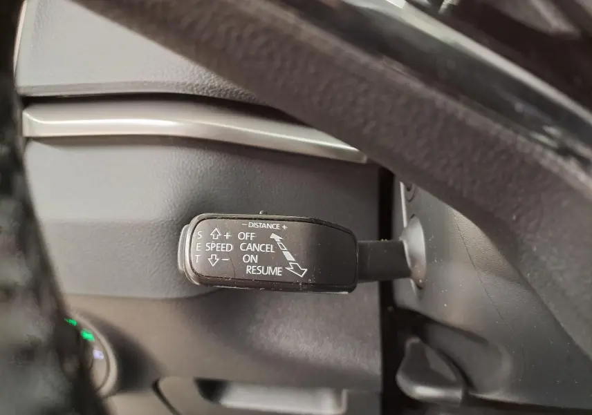 Gros plan sur le commodo de régulateur de vitesse du Skoda Karoq 2023, intérieur gris avec détails en plastique noir.