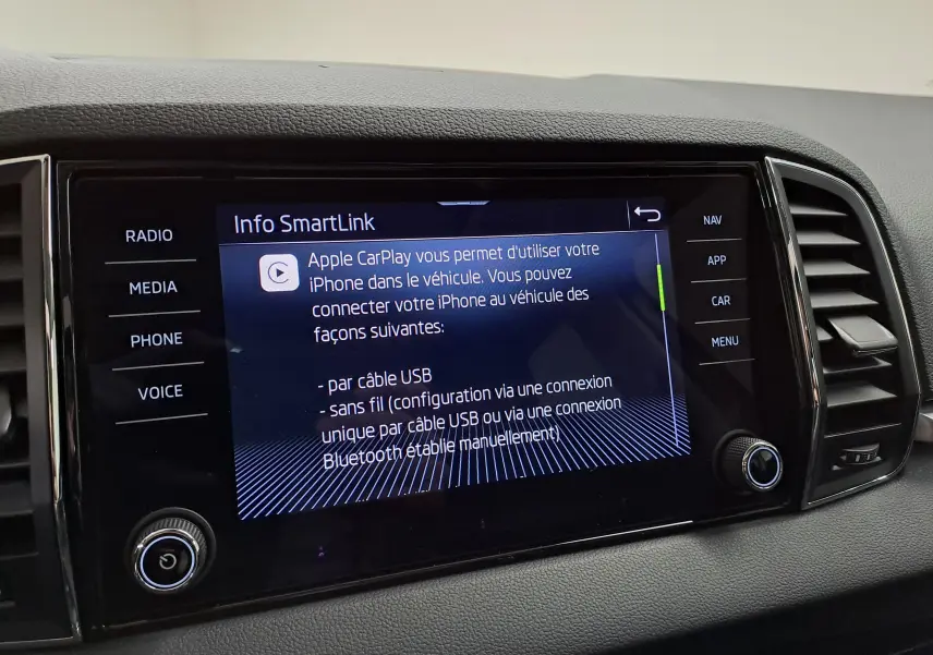 Écran tactile central du Skoda Karoq 2023 affichant les options Apple CarPlay, entouré de commandes noires.
