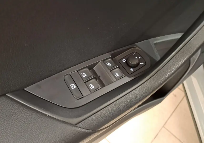 Gros plan sur les commandes de lève-vitres et réglage des rétroviseurs côté conducteur du Skoda Karoq gris perle 2023.