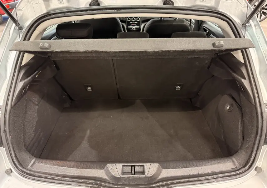 Coffre ouvert vu de l'arrière d'une Renault Mégane IV gris Highland, montrant l'espace de chargement et la plage arrière.