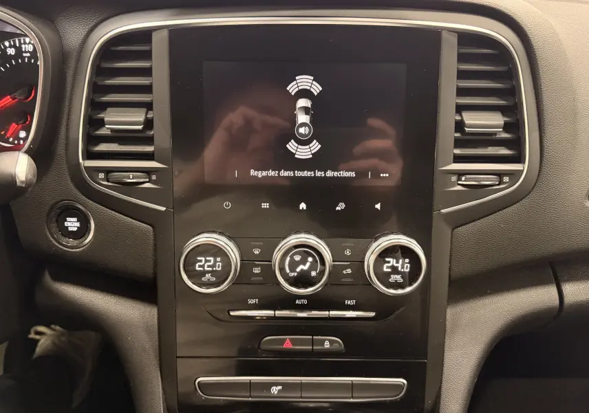 Vue centrale du tableau de bord de la Renault Mégane IV gris Highland, avec écran tactile et commandes de climatisation.