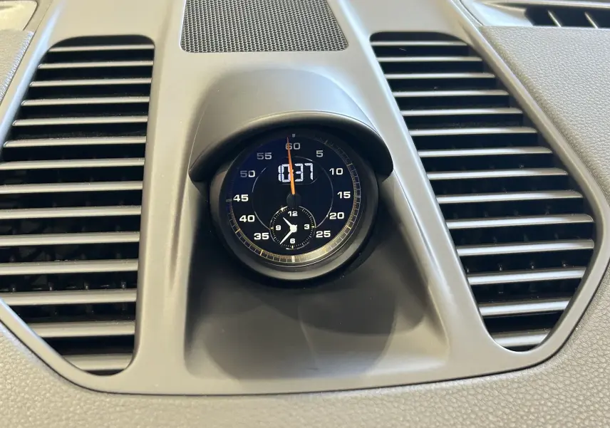 Gros plan sur l'horloge centrale du tableau de bord de la Porsche 911 GT3, entourée de grilles d'aération noires.