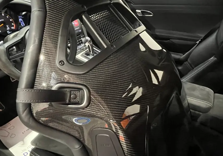 Gros plan sur le siège baquet sport en carbone côté conducteur de la Porsche 911 GT3, avec volant et console visibles en arrière-plan.