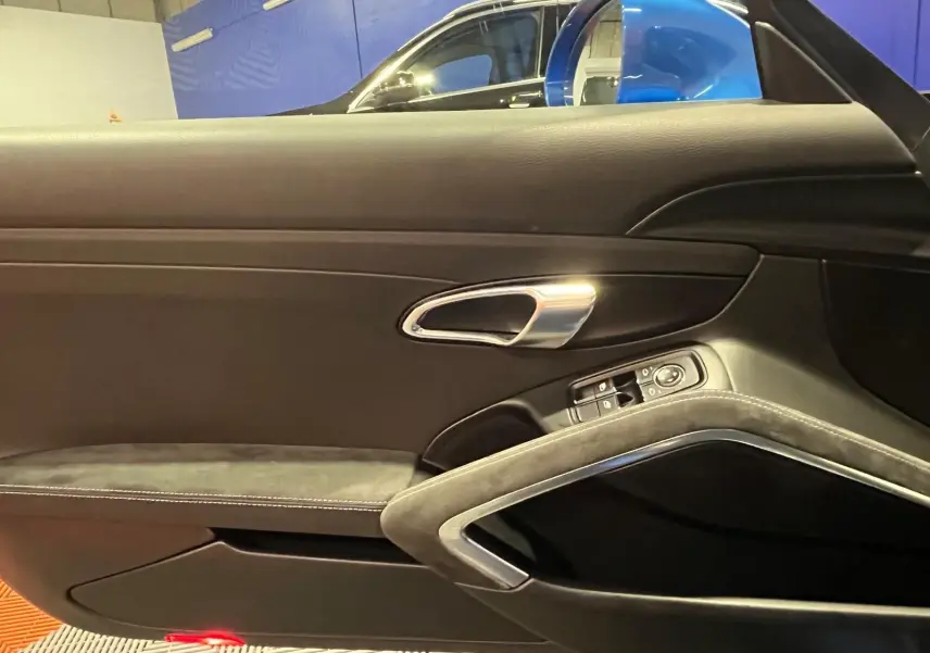 Vue intérieure sur la porte côté gauche d’une Porsche 911 GT3 bleu saphir, avec poignée alu et garniture alcantara.