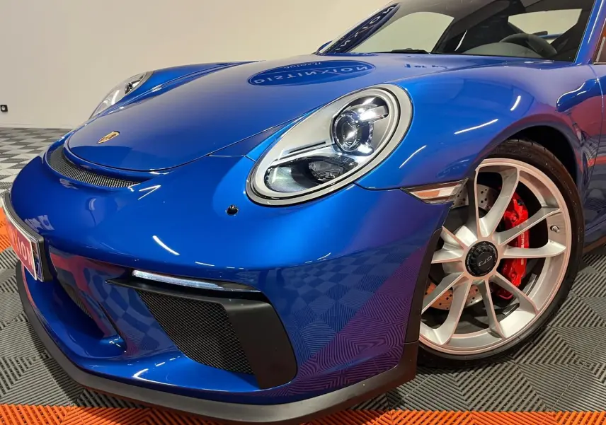 Vue 3/4 avant droit d'une Porsche 911 GT3 bleu saphir avec jantes argentées et étriers de frein rouges.
