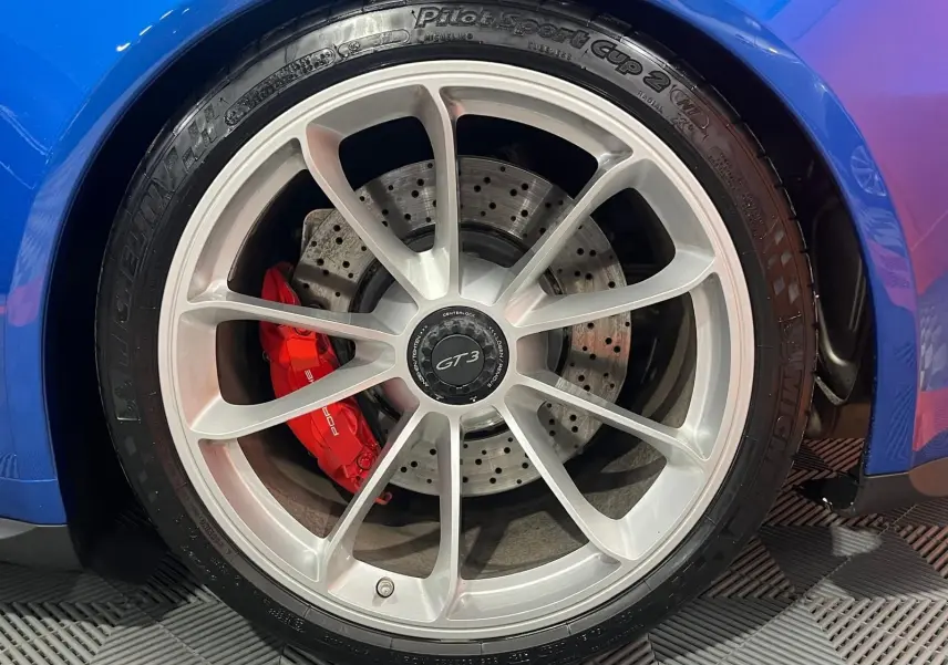 Gros plan sur la roue avant droite de la Porsche 911 GT3 bleu saphir avec étrier de frein rouge et jante argentée.