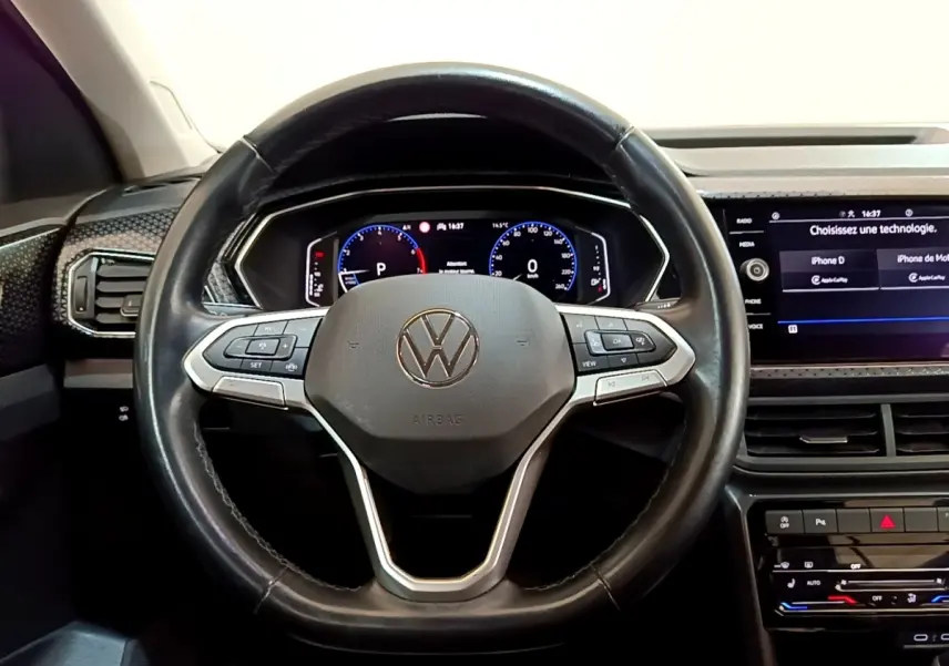 Vue intérieure centrée sur le volant noir en cuir du Volkswagen T-Cross 2022 avec tableau de bord numérique et écran tactile.