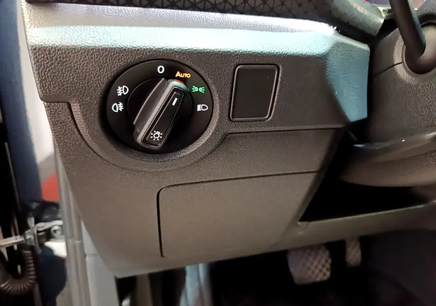 Gros plan sur le bouton de commande des phares à gauche du volant dans l'habitacle du Volkswagen T-Cross noir.