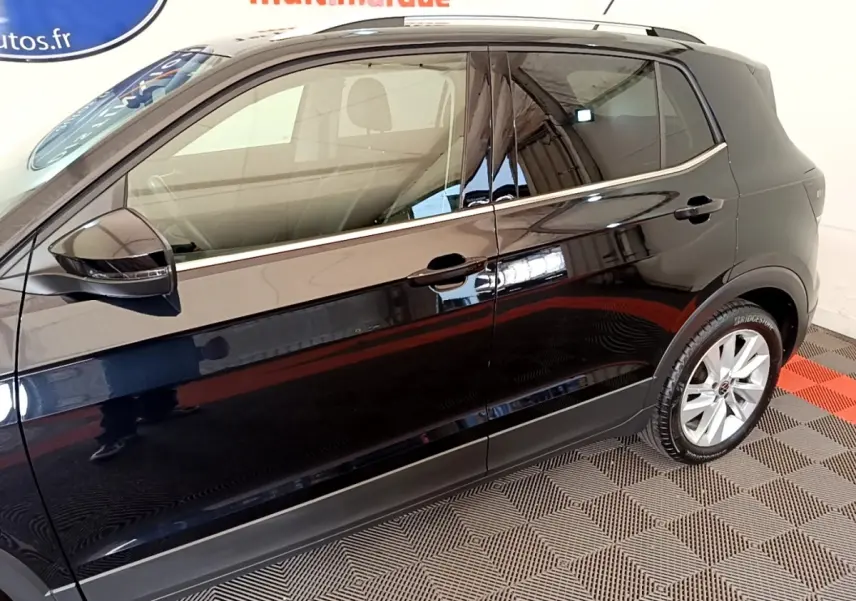 Vue de profil côté gauche d'un Volkswagen T-Cross noir brillant avec jantes alliage et rétroviseur électrique.