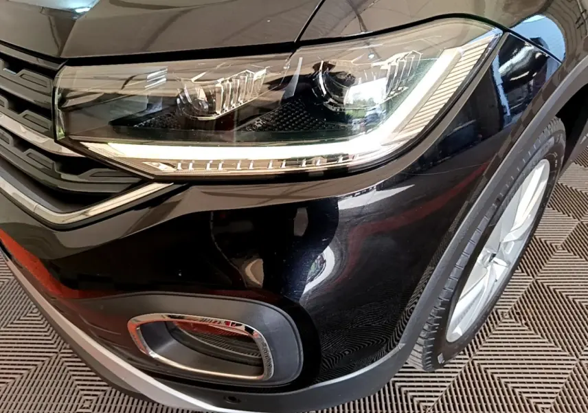 Gros plan sur l'avant droit noir du Volkswagen T-Cross 2022, mettant en valeur le phare LED et la calandre chromée.