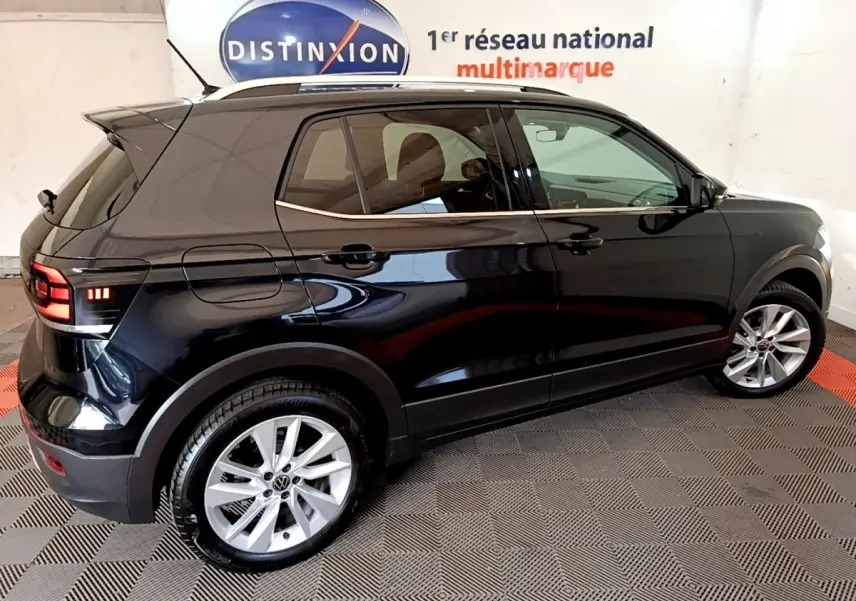 Volkswagen T-Cross noir vue de profil côté droit, avec jantes alliage et vitres teintées en intérieur showroom.