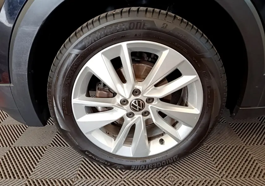 Gros plan sur la roue avant gauche du Volkswagen T-Cross noir, jante alliage argentée à plusieurs branches.