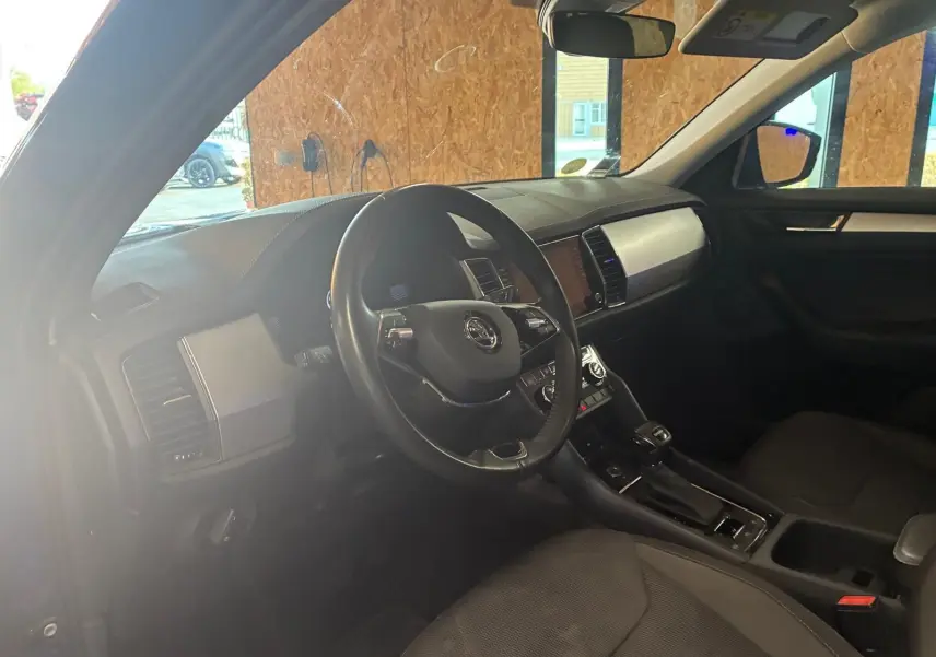 Intérieur noir du Skoda Kodiaq 2023, vue côté conducteur montrant le volant, tableau de bord et console centrale.