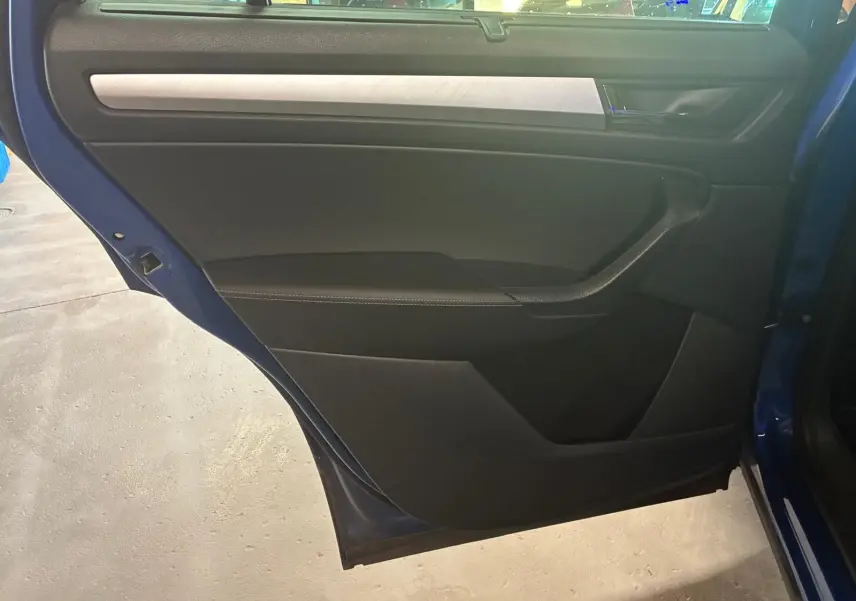 Vue intérieure de la porte arrière gauche d’un Skoda Kodiaq bleu 2023 avec garniture noire et insert argenté.