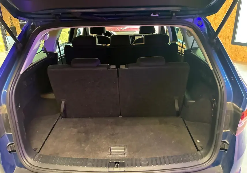 Coffre ouvert d’un Skoda Kodiaq bleu 2023, vue arrière montrant la troisième rangée de sièges relevée.