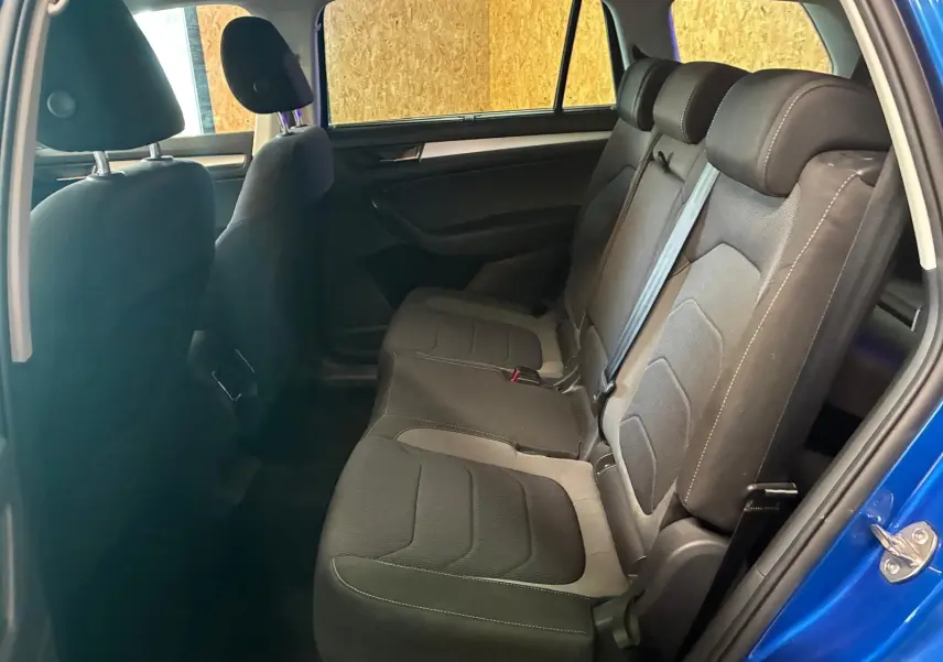 Vue intérieure côté droit des sièges arrière en tissu noir du Skoda Kodiaq bleu 2023, porte arrière ouverte.