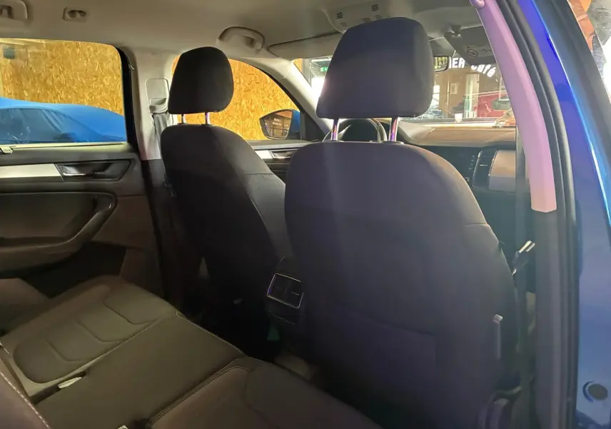 Vue intérieure arrière du Skoda Kodiaq bleu 2023, montrant les sièges noirs en tissu et la console centrale.