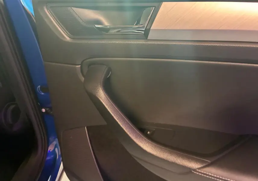 Détail de la porte côté gauche du Skoda Kodiaq 2023 bleu, avec poignée noire et insert décoratif bois clair.