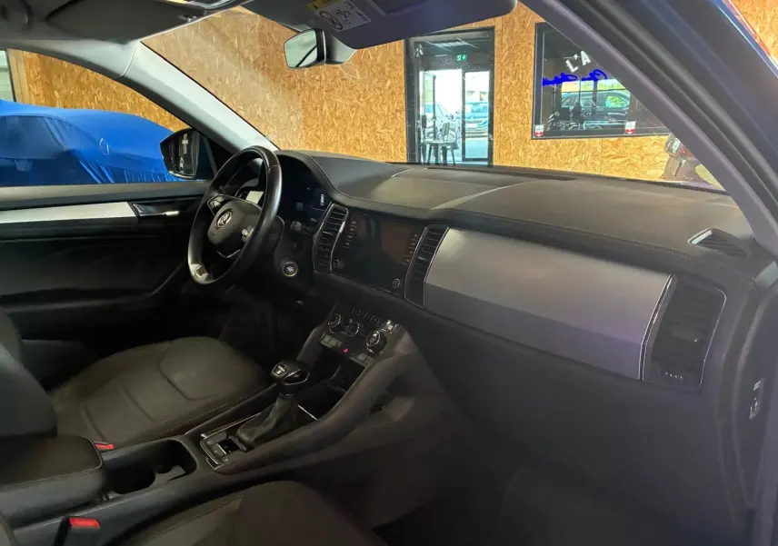 Vue intérieure côté conducteur du Skoda Kodiaq 2023, tableau de bord noir avec inserts métalliques et volant multifonction.