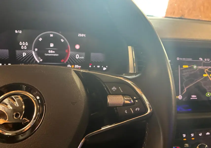 Vue rapprochée du volant noir d’un Skoda Kodiaq 2023 avec affichage numérique et écran GPS en arrière-plan.