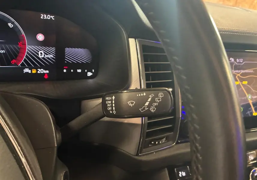 Gros plan intérieur sur le commodo d’essuie-glace côté gauche du Skoda Kodiaq bleu 2023, avec tableau de bord numérique et écran GPS visibles.