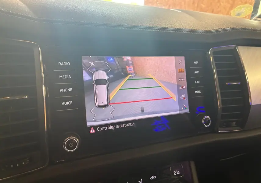 Écran central du Skoda Kodiaq 2023 montrant la caméra de recul avec lignes de guidage colorées.
