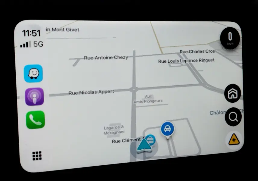Écran de navigation du Toyota Aygo X blanc, affichant une carte avec icônes d’itinéraire et vitesse à 0 km/h.