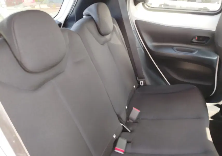 Vue intérieure côté droit des sièges arrière noirs d'une Toyota Aygo X 2023, avec portière et ceintures visibles.