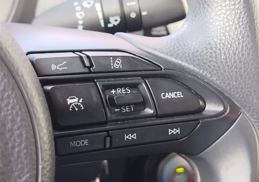Gros plan sur les commandes de régulateur de vitesse au volant noir de la Toyota Aygo X blanche 2023.