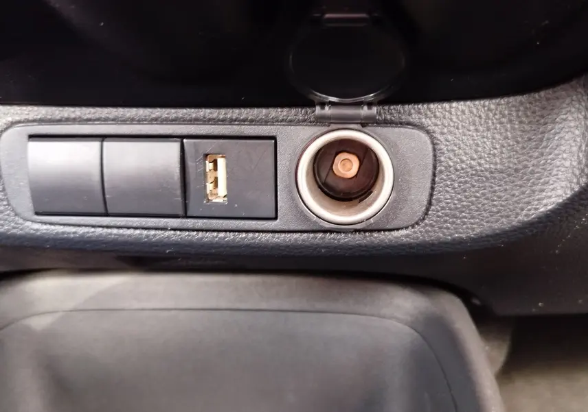 Prise allume-cigare et port USB sur la console centrale d'une Toyota Aygo X 2023, intérieur noir texturé.