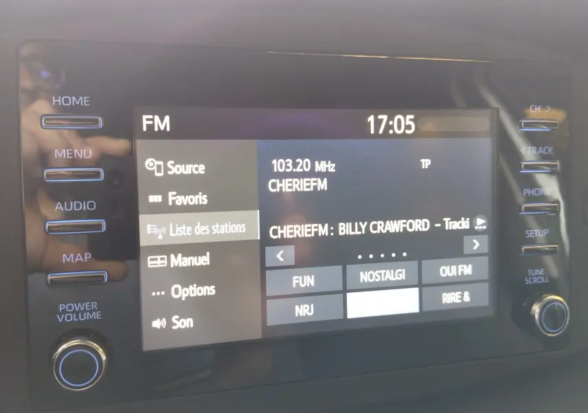 Écran tactile de la console centrale de la Toyota Aygo X affichant la radio FM sur la station Cherie FM à 17h05.