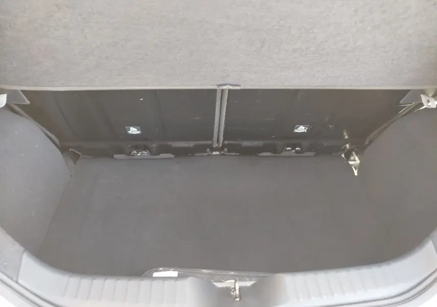 Vue intérieure du coffre noir de la Toyota Aygo X blanc pur, version 2023, avec banquette arrière visible.