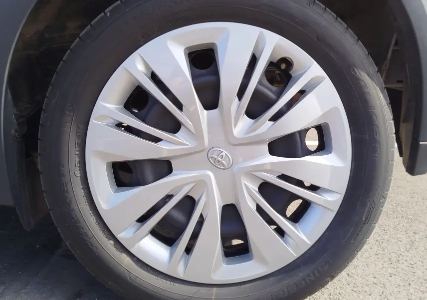 Gros plan sur la jante argentée avec logo Toyota au centre, montée sur un pneu noir de Toyota Aygo X blanc.