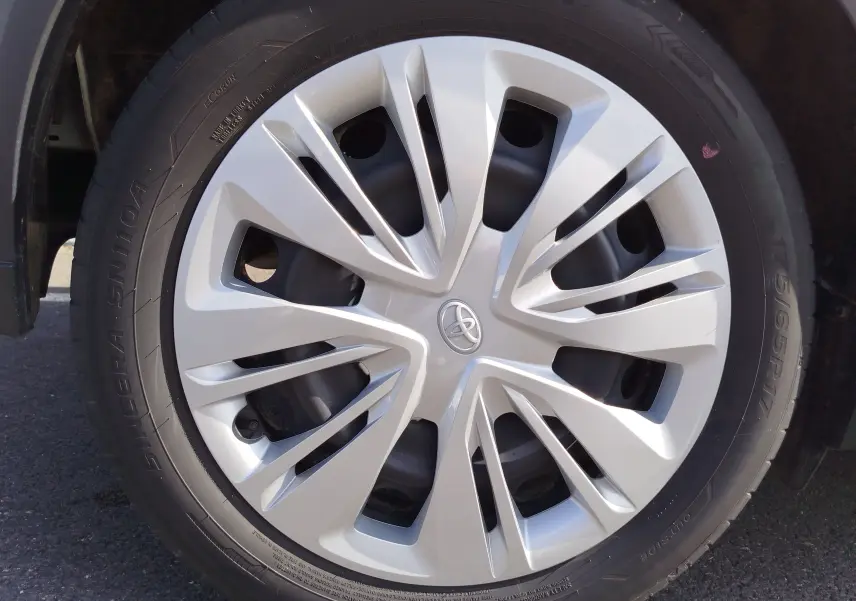 Gros plan sur la jante argentée avec logo Toyota au centre, montée sur un pneu noir d'une Toyota Aygo X blanche.