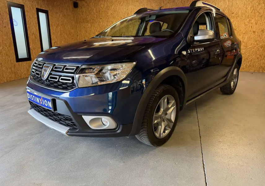 Dacia Sandero Stepway bleu vue 3/4 avant droit, avec badge Stepway sur la porte et jantes alliage.