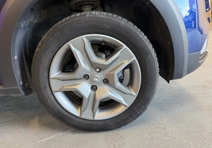 Gros plan sur la roue avant droite d’une Dacia Sandero Stepway bleue de 2019 avec jante alliage et pneu Michelin.
