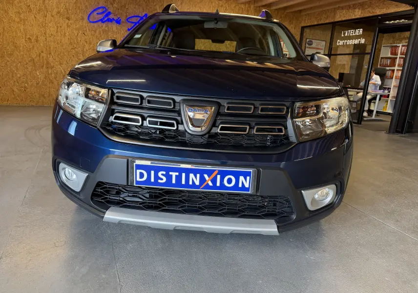 Vue avant d'une Dacia Sandero Stepway bleue 2019, mettant en valeur la calandre noire et les phares larges.